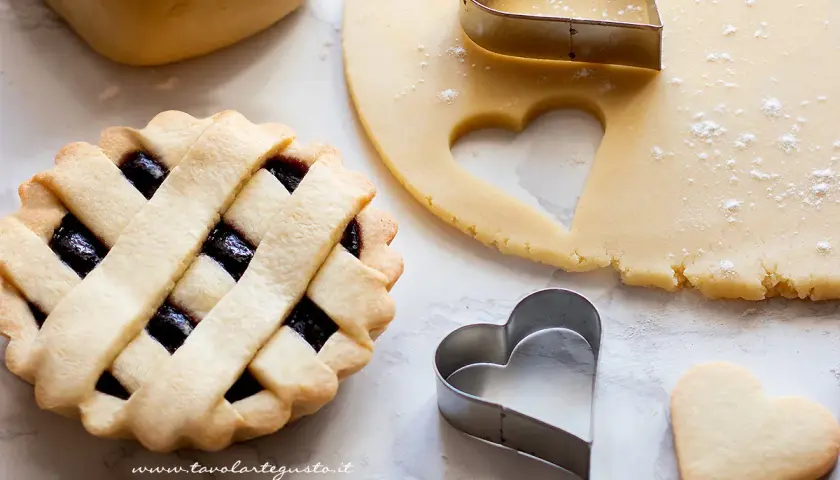 Pasta frolla pronta per essere infornata. La temperatura di cottura è fondamentale per ottenere un risultato perfetto. Cuoricini di frolla e crostata con marmellata.