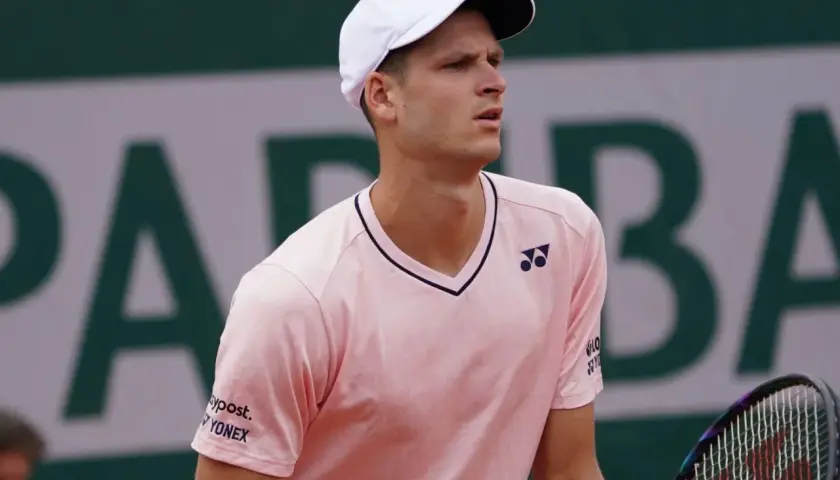 Hubert Hurkacz w różowej koszulce i białej czapce z logo Yonex, gotowy do gry na korcie.