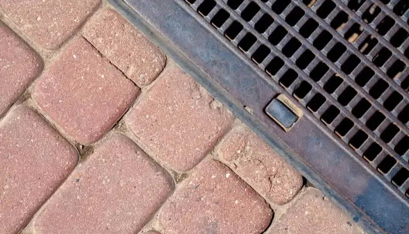 Kostka brukowa i metalowa kratka ściekowa zapewniające sprawne odwodnienie domu.