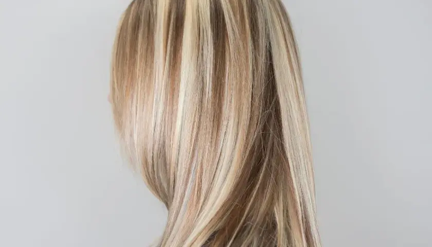Kobieta z pasemkami blond na prostych włosach.
