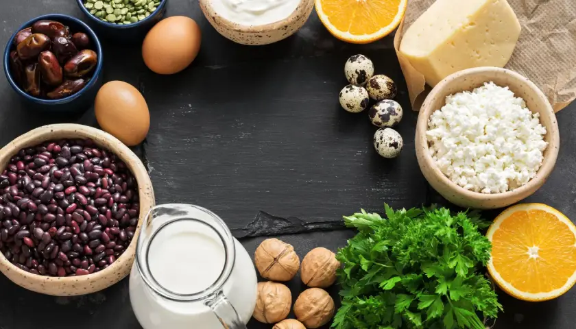 Vielfalt an calcium lebensmittel: Milch, Käse, Joghurt, Eier, Bohnen, Datteln, Nüsse, Orangen und Petersilie.