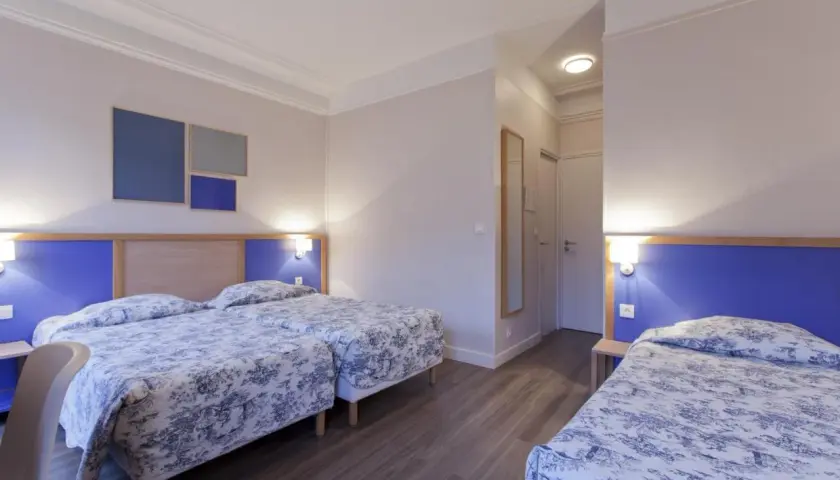 Pokój hotelowy z trzema łóżkami, idealny dla rodziny szukającej odpowiedzi, gdzie najlepiej nocować w Paryżu.