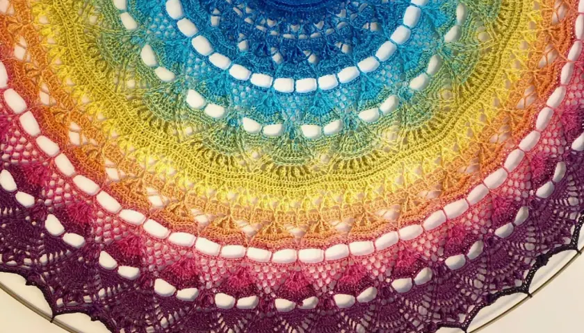 Kolorowa, tęczowa mandala z koronki, niczym tatuaż mandala między piersiami, ozdobiona misternym wzorem.