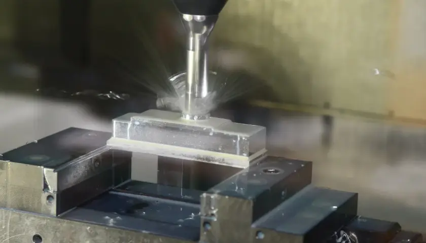 Precyzyjne frezowanie aluminium na maszynie CNC. Chłodziwo rozpryskuje się wokół obrabianego elementu.