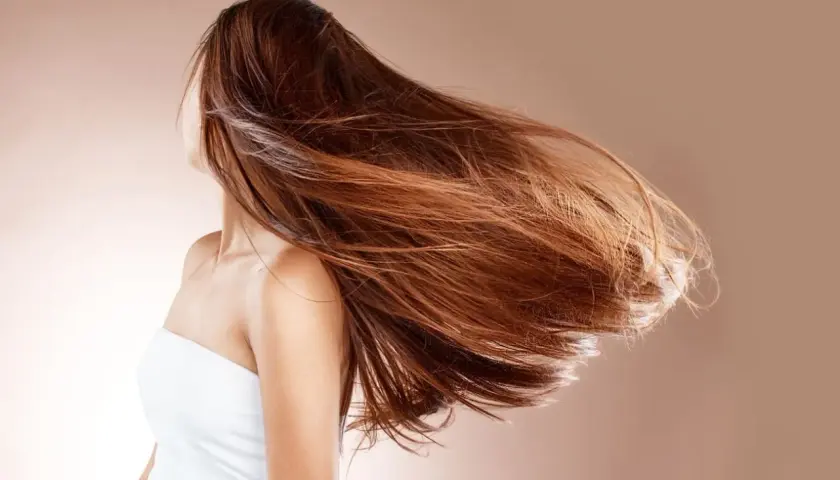 Mujer con cabello largo y castaño moviéndose con el viento. ¿Cuánto crece el pelo en un año mujer?