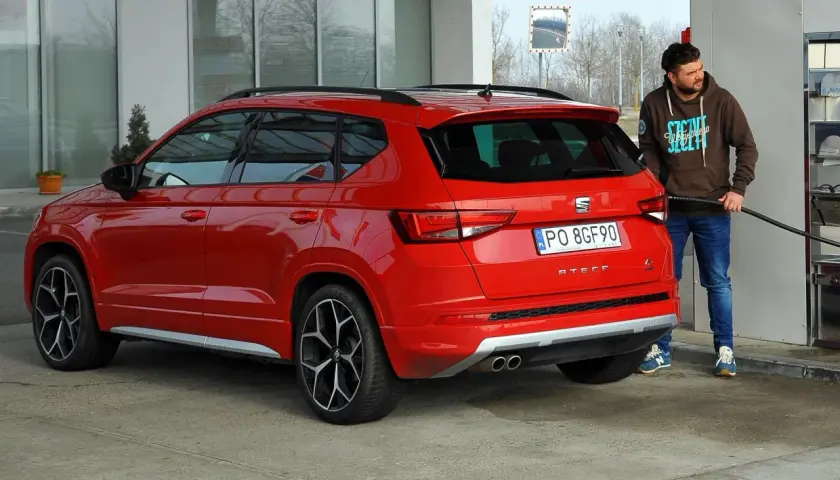 Mężczyzna tankuje czerwonego SUV-a. Zastanawiasz się, ile pali suv? Ten model Seat Ateca właśnie dostaje paliwo.