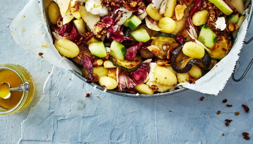 Ein köstlicher lauwarmer Gnocchi-Salat mit gegrilltem Gemüse, Radicchio, Birne und Nüssen, serviert mit Honig.