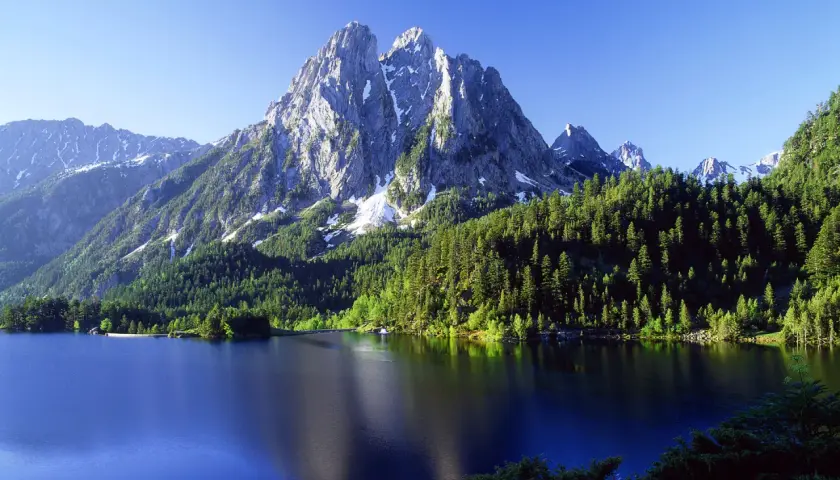 El estany de Sant Maurici, un lago alpino rodeado de bosques de pinos y picos nevados, refleja la majestuosidad de la naturaleza.