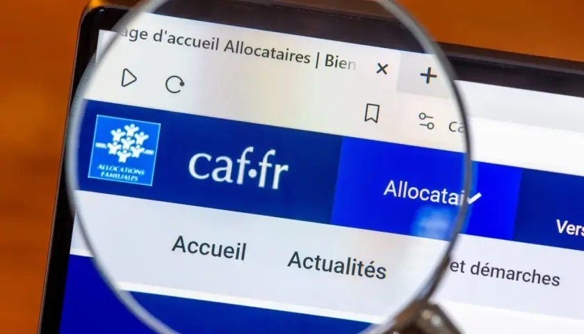 Loupe sur l'écran d'un ordinateur affichant le site caf.fr, page d'accueil des allocataires. L'accès aux informations est facilité.
