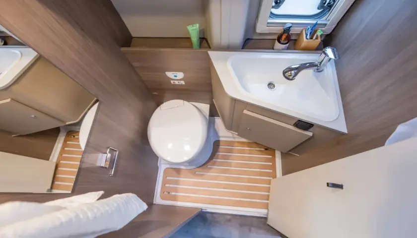 Salle de bain arrière de camping-car : toilette, lavabo et douche intégrée. Pratique pour les voyages.