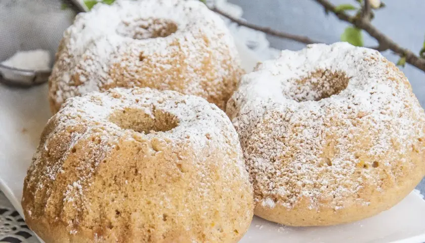 Trzy puszyste muffinki piaskowe posypane cukrem pudrem, gotowe do podania.