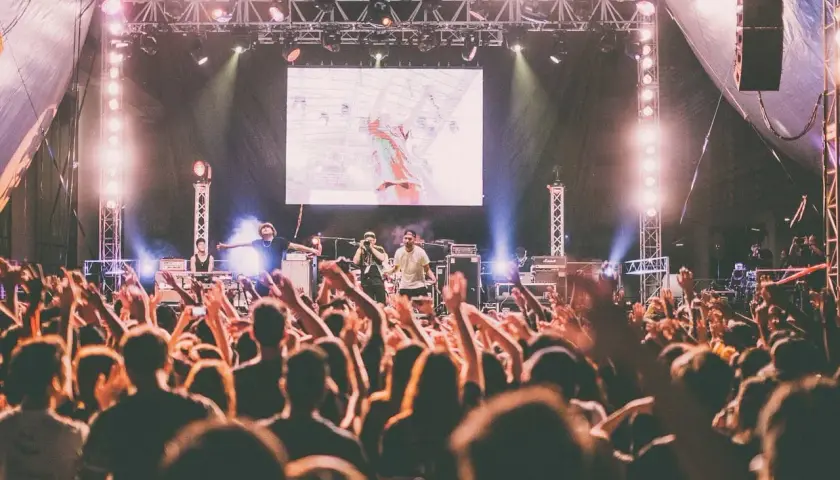 Koncert australijskiego zespołu rockowego. Tłum szaleje, ręce w górze, światła sceniczne.