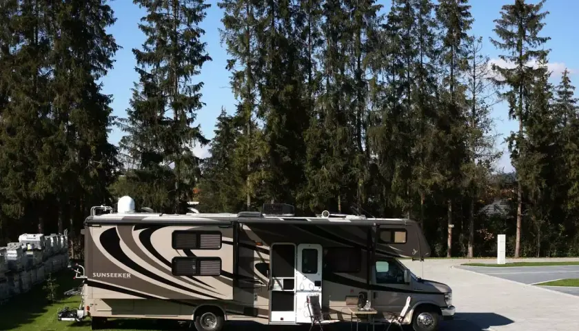Kamper Sunseeker zaparkowany na campingu Gorący Potok, otoczony wysokimi sosnami.