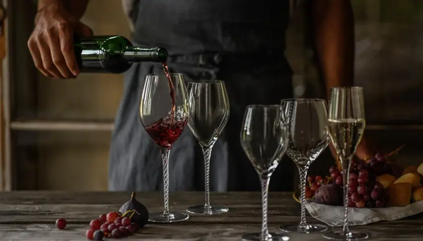 Skutki napowietrzania wina (dekantacja) widoczne podczas przelewania do karafki. Wino w kieliszku, obok winogrona i figi.