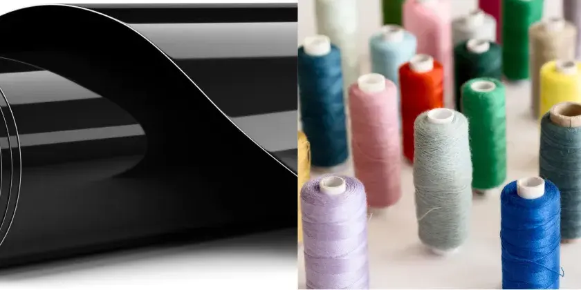 Rouleau de vinyle noir brillant pour flocage textile, à côté de bobines de fil colorées.