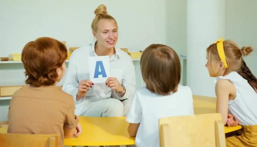 Nauczycielka pokazuje dzieciom literę "A" na karcie.