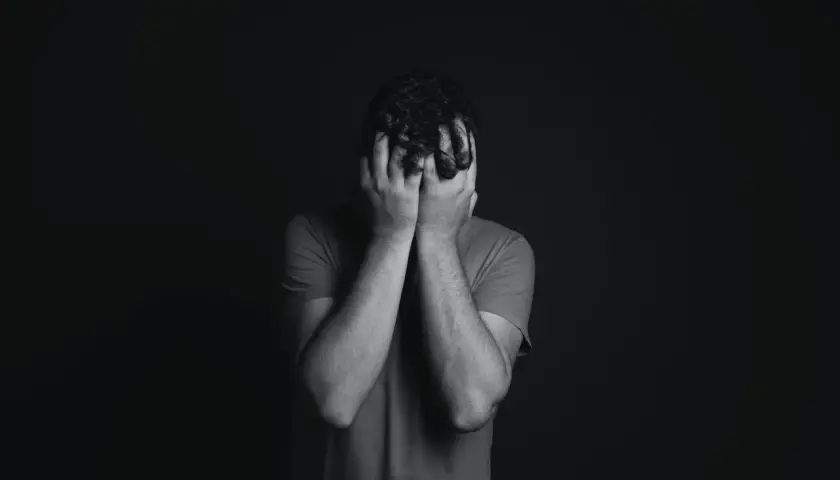 Uomo con le mani sul viso, in un momento di profonda tristezza. Finalmente sono guarito dalla disfunzione erettile.
