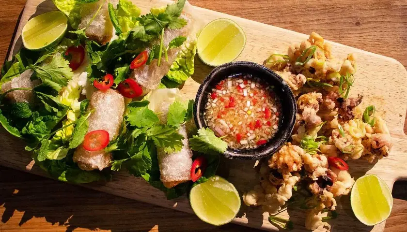 Krispiga cha gio med färska örter, lime och en dippsås. Bredvid ligger friterad bläckfisk.
