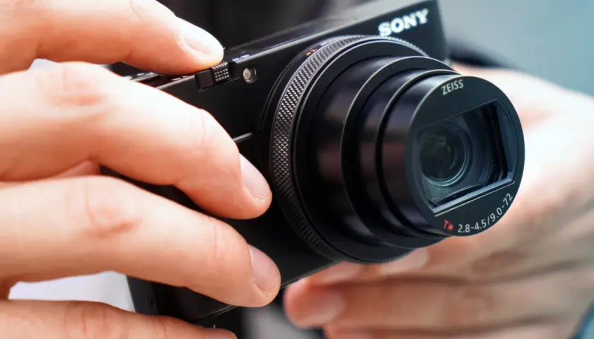 Dłonie trzymają aparat Sony RX100 VII z obiektywem Zeiss.