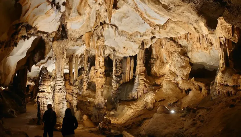Dwie osoby zwiedzają imponujące jaskinie w Polsce, podziwiając stalaktyty i stalagmity.