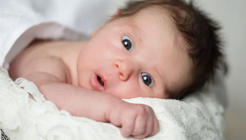 Un neonato con occhi spalancati, che sembra scoprire il mondo. La sua espressione curiosa cattura il momento in cui iniziano a vedere i neonati.