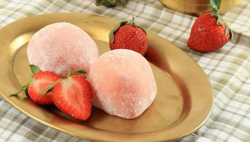 Różowe mochi z truskawkami na złotym talerzu. Idealne do wypróbowania, gdy szukasz przepisu na mochi.