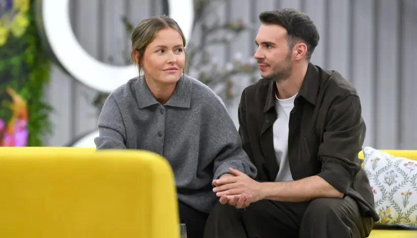 Olga Frycz i jej partner, Tomasz Kwaśniewski, siedzą obok siebie na kanapie, trzymając się za ręce.