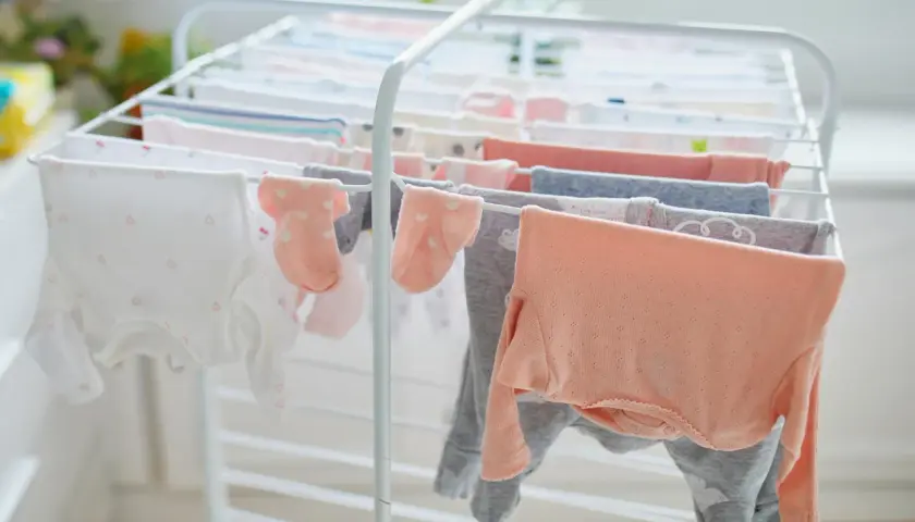 Suszenie ubranek dla noworodka na suszarce. Czy trzeba prasować ubranka dla noworodka? Delikatne body i skarpetki schną, czekając na maluszka.