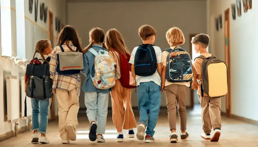 Dzieci z plecakami idą korytarzem. Czas na wystawienie ocen na 1 semestr!