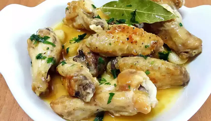 Alitas de pollo al ajillo, doradas y jugosas, bañadas en una salsa aromática con ajo y perejil fresco. Un plato delicioso.