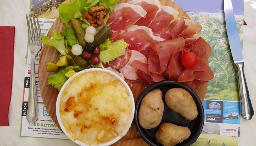 Assiette généreuse de charcuterie, fromage gratiné, pommes de terre et crudités, un vrai plat savoyard pour les gourmands.
