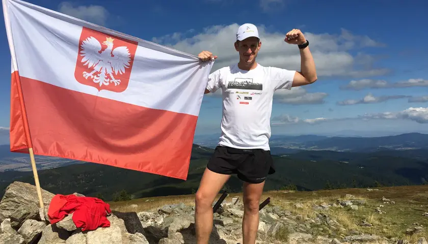Mężczyzna z polską flagą na szczycie, zdobywając diadem polskich gór. Wykaz szczytów zdobyty!