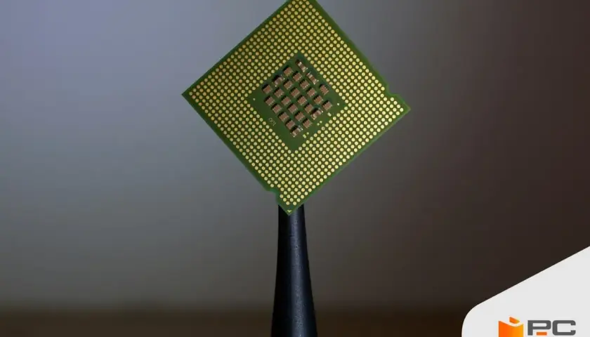 Procesador Intel Core i5, con sus pines dorados y el chip central visible, sostenido por una herramienta.