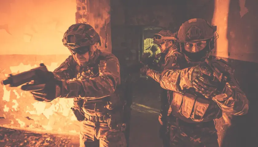 Żołnierze w taktycznym kamuflażu, z bronią w rękach, ćwiczą **CQB co to** jest walka w bliskim kontakcie w ciasnych pomieszczeniach.