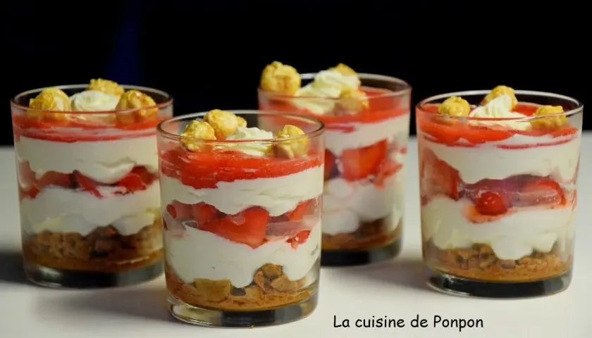 Quatre verrines fraise mascarpone superposant biscuits émiettés, crème onctueuse, fraises fraîches et coulis, surmontées de chantilly et de pop-corn caramélisé.