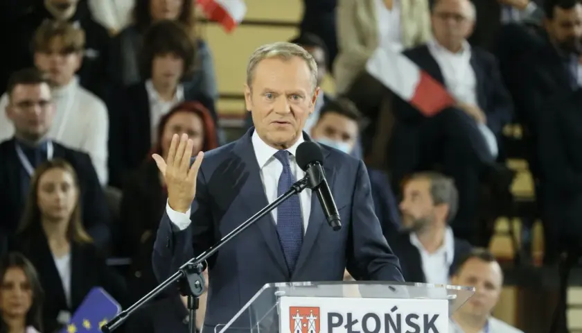 Donald Tusk przemawia na konwencji po w Płońsku. W tle widzowie z polskimi flagami.