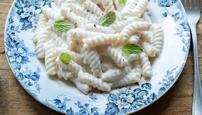 Fusilli conditi con una cremosa salsa alla ricotta, guarniti con foglie di menta fresca. Un piatto semplice e gustoso.