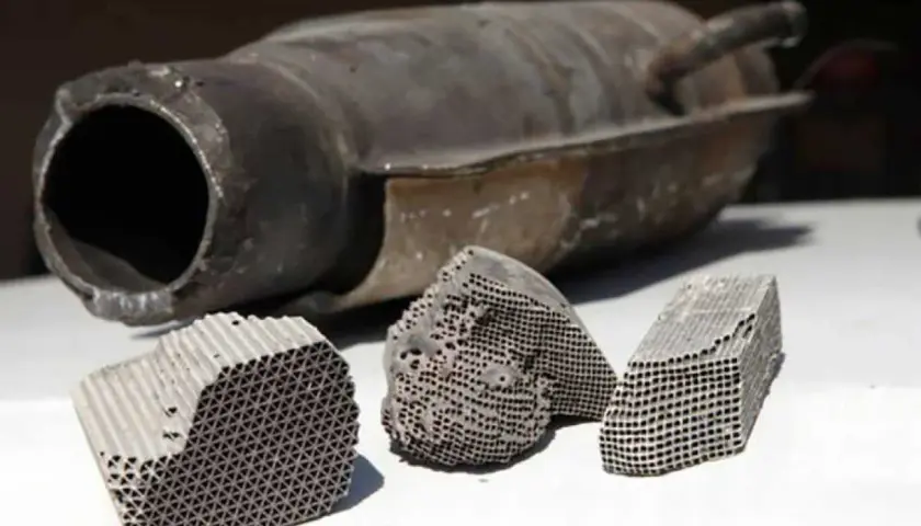 Rozcięty katalizator samochodowy z widocznym wkładem ceramicznym o strukturze plastra miodu.