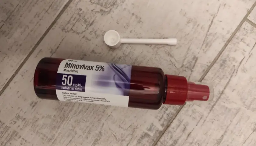 Butelka Minovivax 5% z aplikatorem na drewnianym tle. Preparat na porost włosów.