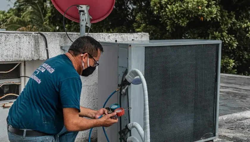Technik sprawdza sprzęgło klimatyzacji, podłączając manometry do jednostki zewnętrznej.