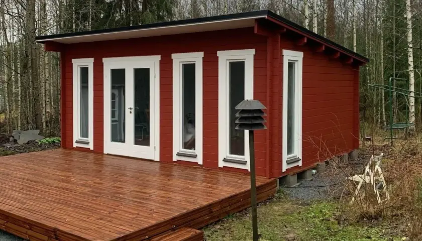 Rött attefallshus med altan i skogsglänta. Perfekt för dig som vill bygga attefallshus och njuta av naturen.