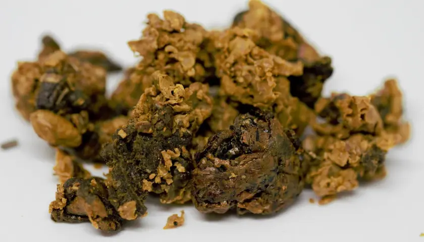 Cumuli di propoli grezza, una sostanza resinosa raccolta dalle api, con sfumature marroni e dorate. Cos'è la propoli delle api? È un dono della natura.