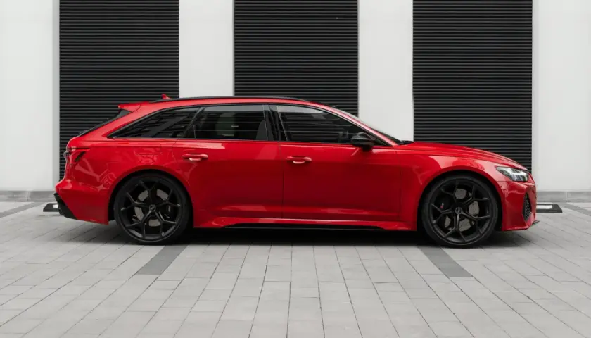 Czerwone Audi RS6 Avant na czarnym tle z białymi pasami. Zastanawiasz się nad audi rs6 cena?
