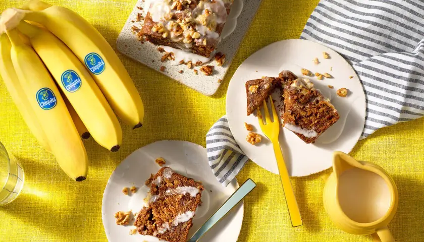 Fette di banana bread senza uova, guarnite con glassa e noci, pronte per essere gustate.