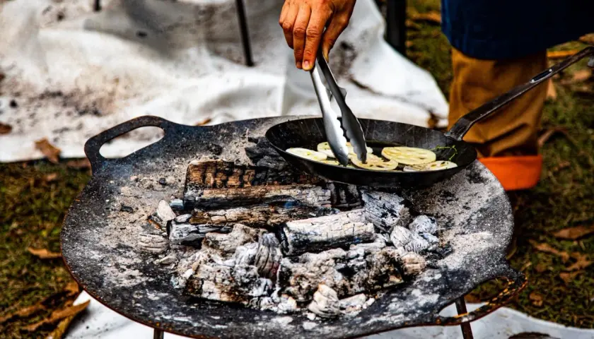 Cuisson de rondelles de lotus dans une poêle sur un feu de bois. La température du barbecue est parfaite pour cette cuisson.