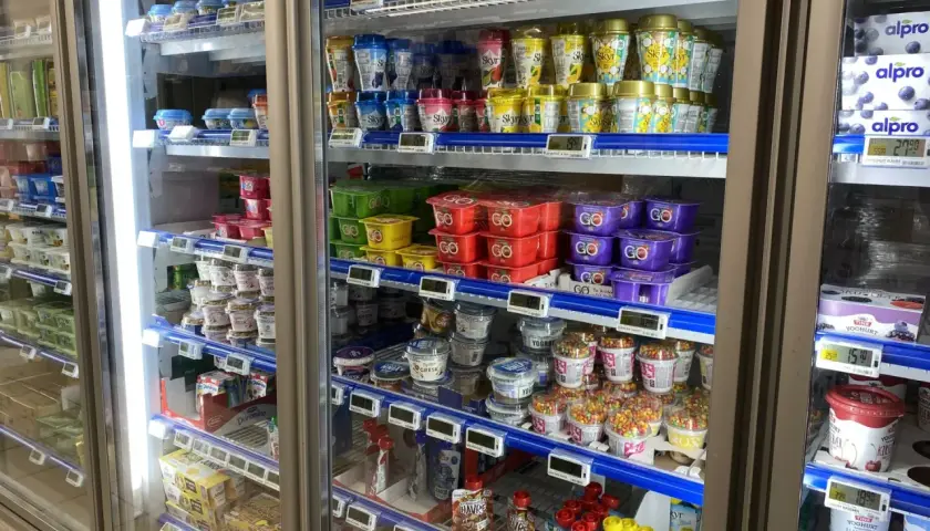W lodówce w Norwegii widać jogurty i desery. Ceny w sklepach są widoczne na etykietach, np. 27,90 za jogurt.