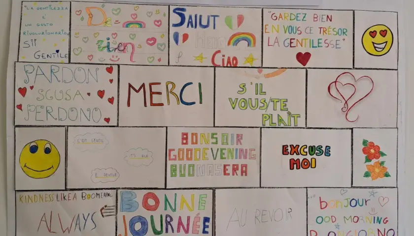 Il muro delle parole gentili: "La gentilezza è un gesto rivoluzionario". Frasi gentili in inglese e altre lingue celebrano la cortesia.