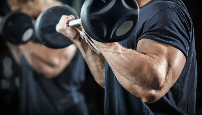 Mężczyzna ćwiczy bicepsy z hantlami, realizując swój trening split.