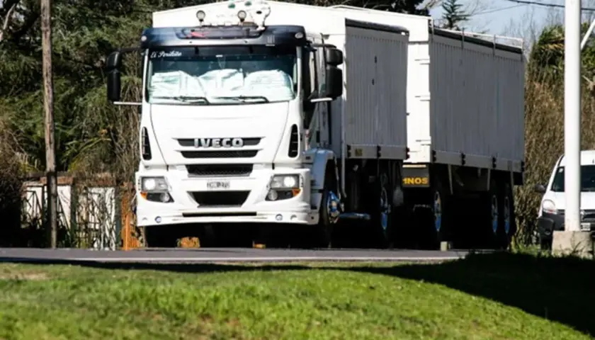 Biała ciężarówka Iveco z naczepą jedzie drogą. Kierowca ciężarówek wyrusza w długą trasę.