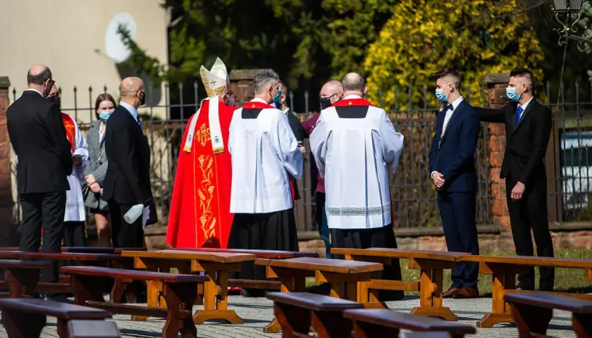 Biskup w czerwonej kapie i ministranci podczas ceremonii bierzmowania.